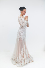 Fototapeta premium A young Southeast Asian bride in an elegant lace wedding gown prays with hope and faith, seeking blessings for her upcoming marriage.