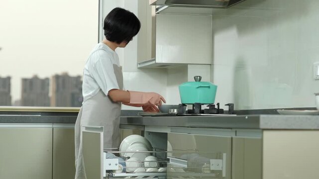 Focused housewife homemaker woman wearing rubber protective gloves arranging loading dishes, drying for plates and mugs in kitchen cabinet cupboard, doing housework maintain organized home
