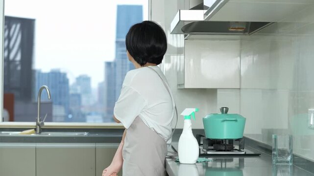 Exhausted housewife homemaker woman wearing gloves suffering back, shoulder, ache, waist, neck pain when cleaning kitchen cupboards with rag for dust dirt, bacteria or germs with spray bottle sponge