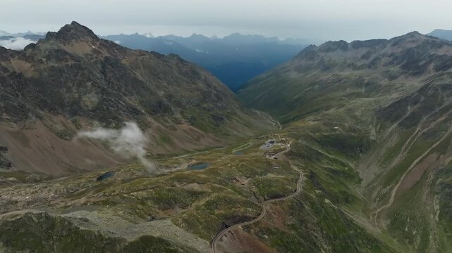 Beautiful aerial landscape of the Timmelsjoch High Alpine Road in Austria where a car travels through dramatic mountain scenery and alpine wilderness