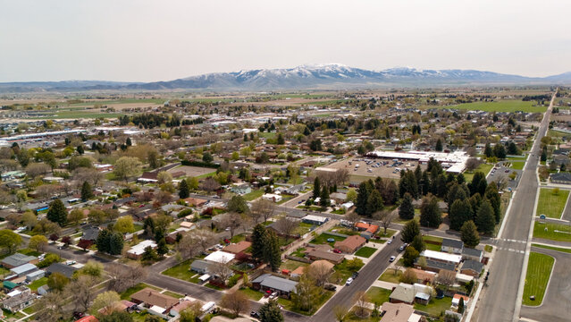 Aerial view of a residential neighborhood with tree lined streets and mountains in the distance.