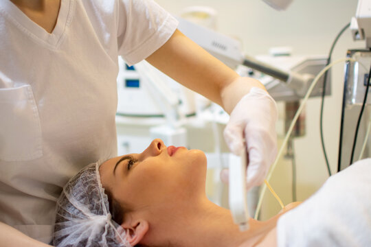 Close up of aesthetician doing microcurrent facial lifting therapy on woman neck