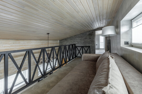 Mezzanine Floor Interior with Sofa, Metal Railing, and Sloped Ceiling