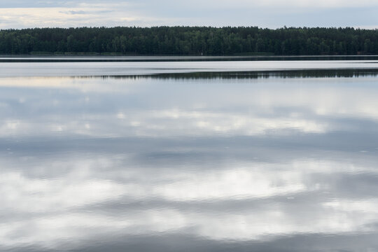 Perfect Mirror Reflection of Clouds on Calm Lake with Forest Horizon