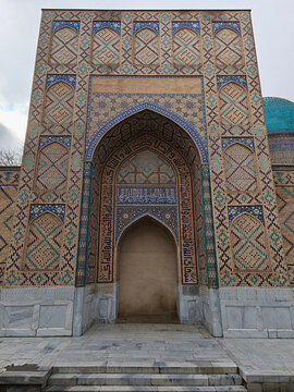 Bibi-Khanym Mosque entrance portal with intricate mosaic tilework in Samarkand. Monumental Timurid architecture featuring geometric patterns and calligraphy under an overcast sky. Ideal for travel.