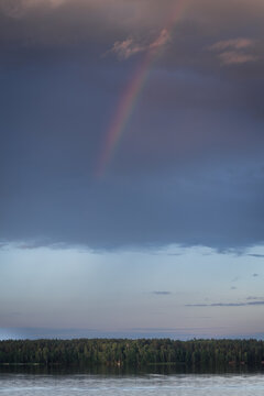 Sunset Landscape with Rainbow over Calm Lake and Forest