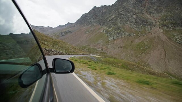 A car drives along a winding mountain road in the Austrian Alps an ascent of the Timmelsjoch High Alpine Road.
