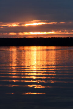 Dramatic Sunrise over Calm Lake with Golden Water Reflection