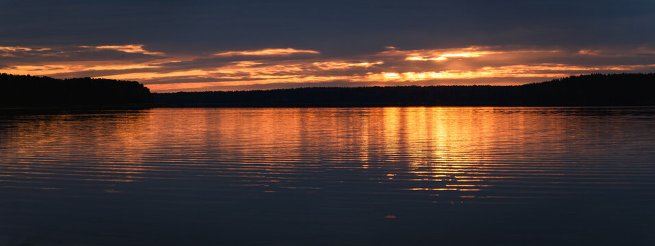 Dramatic Sunrise over Calm Lake with Golden Water Reflection