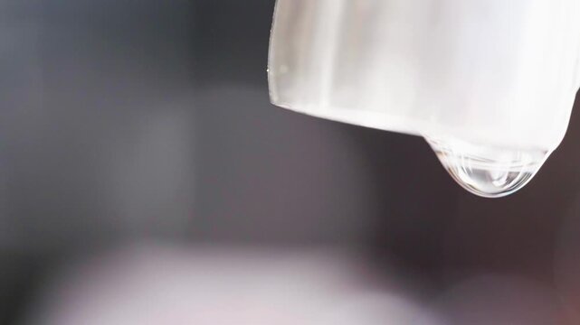 Close up macro of a running dripping tap. Water flowing and bubbling. Tap water silver kitchen fixtures,