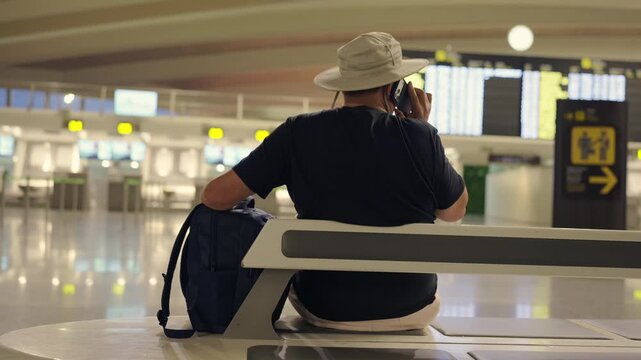 Tourist traveler man talking on phone at airport terminal waiting for flight