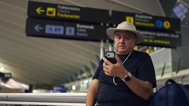 Mature traveler video calling on smartphone in airport