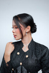 Side profile portrait of an elegant Indonesian woman in a black lace kebaya. © Saddha Visual