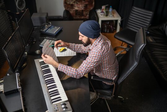 Young man composing music at dim home studio desk