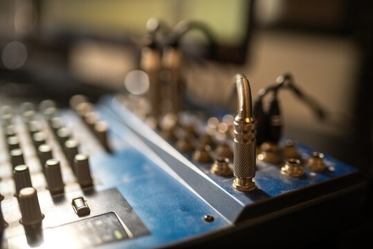 Close-up of audio mixer panel with cables and metal knobs