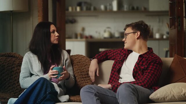 Mother talking with her teenage son over tea, spending quality time together