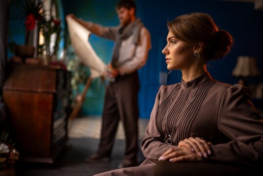 Victorian woman in parlor preparing for portrait with artist in background