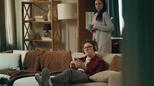 Shocked mother discovering her teen son using a disturbing phone app at home