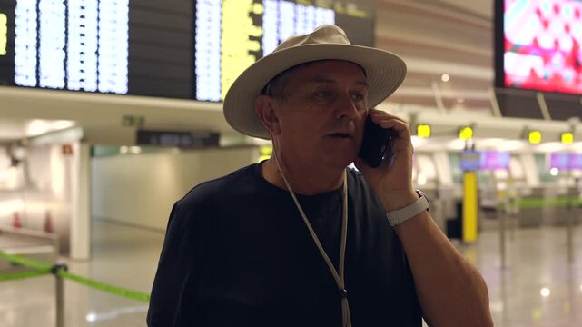 Mature tourist man talking on phone at airport terminal