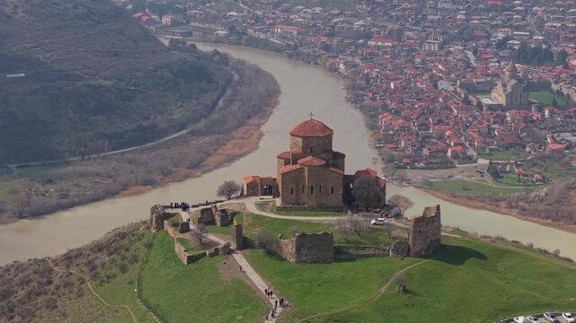 Panoramic spring view of Jvari Monastery overlooking lush green terrain and the river flowing below near the historic town of Mtskheta.