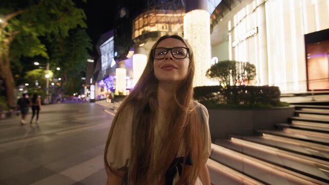 Tourist walking through illuminated streets of downtown Singapore surrounded by glowing shop windows modern city architecture and unforgettable nightlife in Asia 