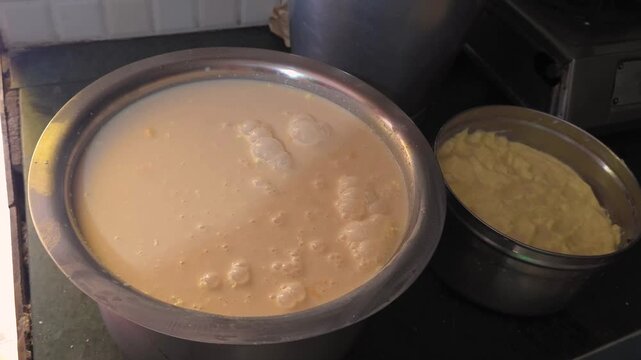 Metal bowls with creamy liquid and dough in kitchen close-up of kitchenware 