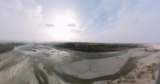 Sweeping aerial panorama of the Trebbia riverbed with the historic village of Rivalta in Italy