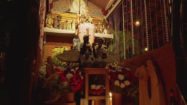 Camera pans down revealing a richly decorated devotional altar with sacred statues, candles, flowers and ceremonial ornaments inside a community sanctuary in Chapada dos Veadeiros, Goi&aacute;s, Brazil.