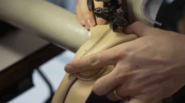 Close up of a leather baseball glove seam being stitched on an industrial sewing machine