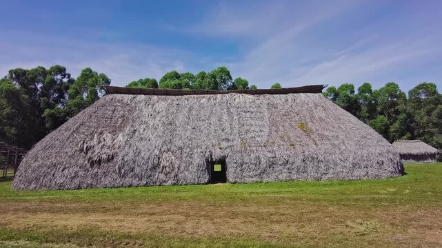 Pan down establishing shot reveals a traditional oca with a monumental sap&eacute; thatched roof surrounded by Cerrado woodland in Chapada dos Veadeiros, Goi&aacute;s, Brazil.