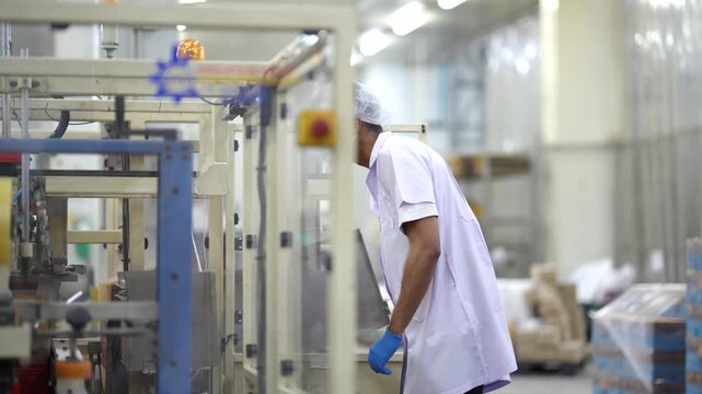Quality control inspector checking can conveyor line and recording inspection results on tablet in food factory. Quality inspection, food safety, production process, manufacturing, factory operations.