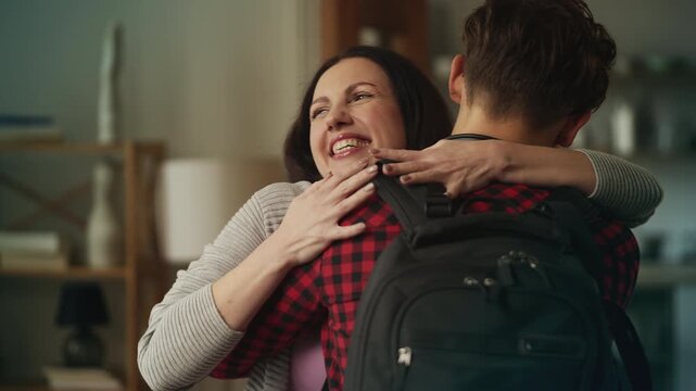 Smiling mother embracing her son returning home from college, happy reunion