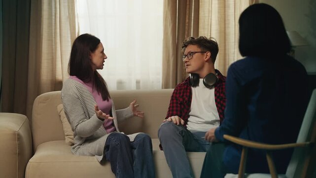 Unhappy teen boy arguing with his mom during a therapy session, family conflict