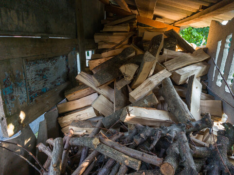 Pile of Dry Chopped Firewood Stored under Shed for Winter Heating
