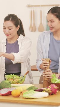 Happy young lesbian couple preparing a healthy fresh vegetable salad together in the modern kitchen.