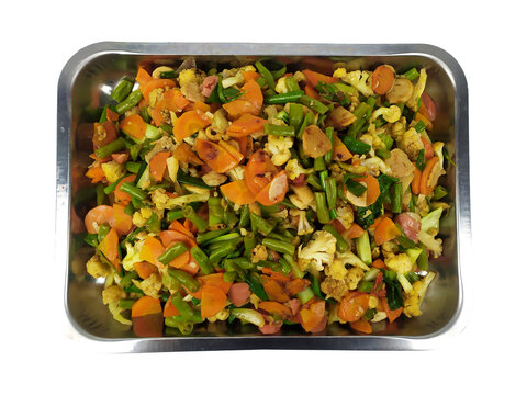 Stir fried mixed vegetables with sliced sausage in metal tray on transparent background