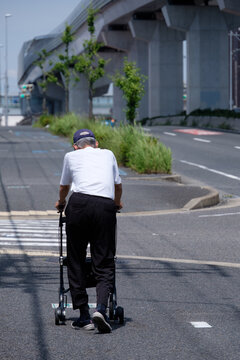 シルバーカーを押しながら歩道を歩く高齢男性