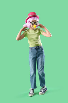 Funny little girl in disguise on green background. April Fools Day celebration