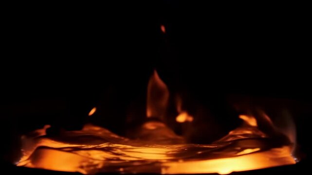 Close-up view of vibrant orange and yellow flames dancing above glowing embers in a dark setting.