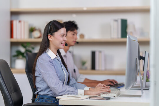 Asian female call center agent typing on computer keyboard at office desk