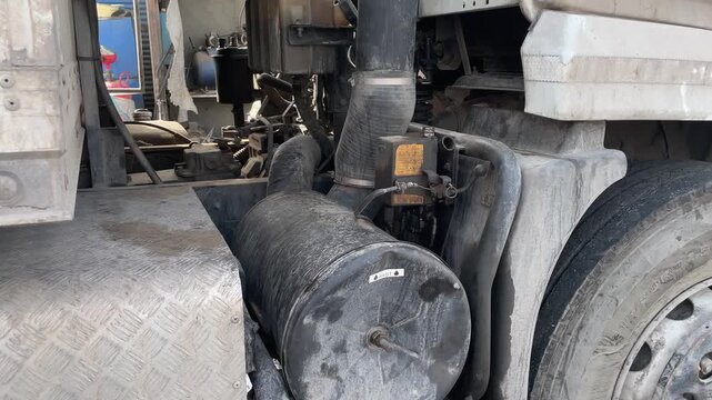 Dirty truck fuel tank and chassis covered with dust and road grime before washing, highlighting commercial vehicle maintenance, industrial transport equipment and cleaning preparation process.