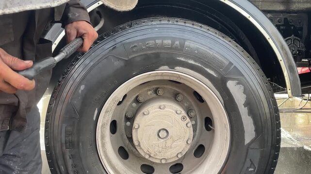 Worker finishing professional cleaning on a truck wheel, leaving a polished tire and rim with a spotless appearance, symbolizing fleet maintenance, transport care and quality service.