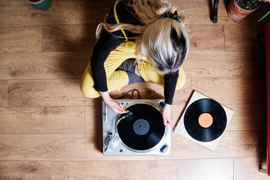 Woman using turntable while sitting on floor