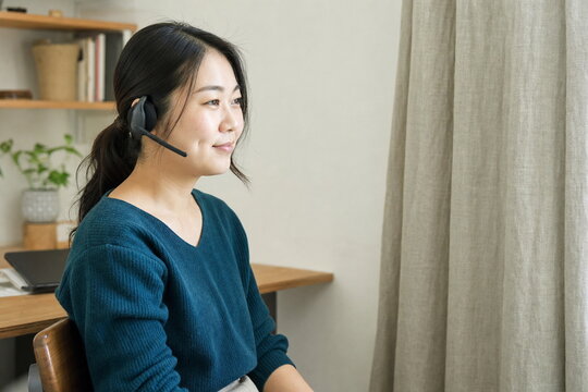 自宅風ワークスペースで問い合わせに対応するヘッドセット姿の女性