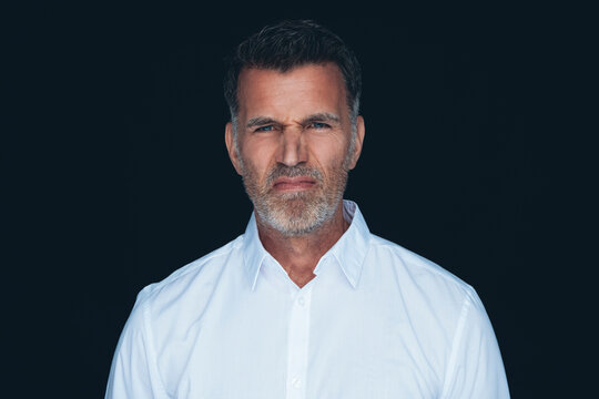 Portrait of man wrinkling nose in front of black background