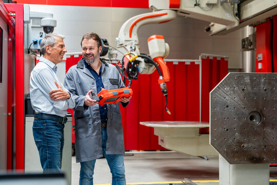 Mature engineer and senior manager inspect industrial robot in factory