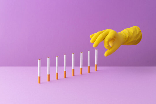 Hand shoving cigarettes in a row, creating a domino effect