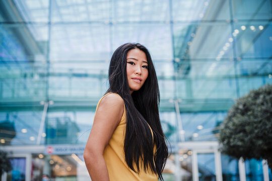 Confident mid adult woman standing in front of modern building
