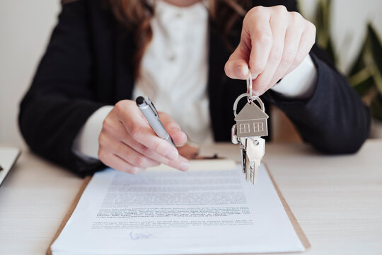 Saleswoman holding house keys and pen at office