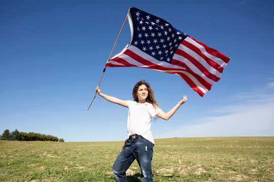 Girl holding American flag on field in remote landscape